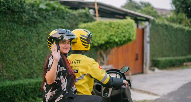 Passenger waving while riding a Maxim motorcycle taxi